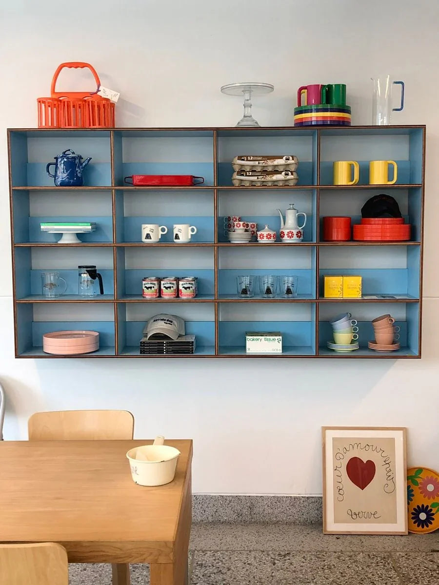Colorful open shelving with mugs, dishes, decor, and dining table in a modern Austin kitchen.