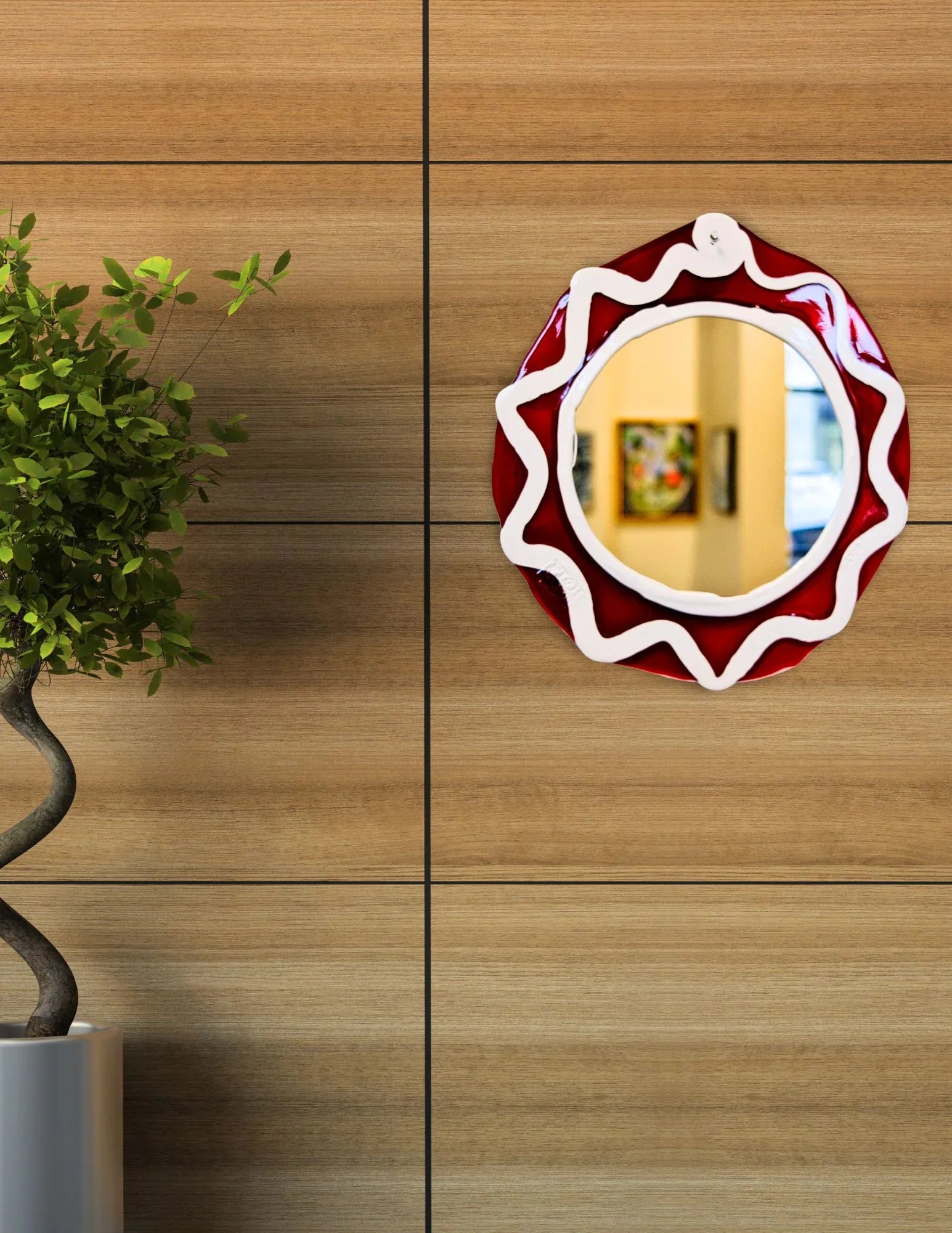 Round red and white mirror on wooden wall with potted plant, modern home decor