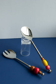 Beaded Serving Utensils by Yam, a pair of stainless steel servers with handles strung from upcycled wooden beads