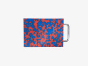 Small red and blue marbled cutting board with chrome handle on white background