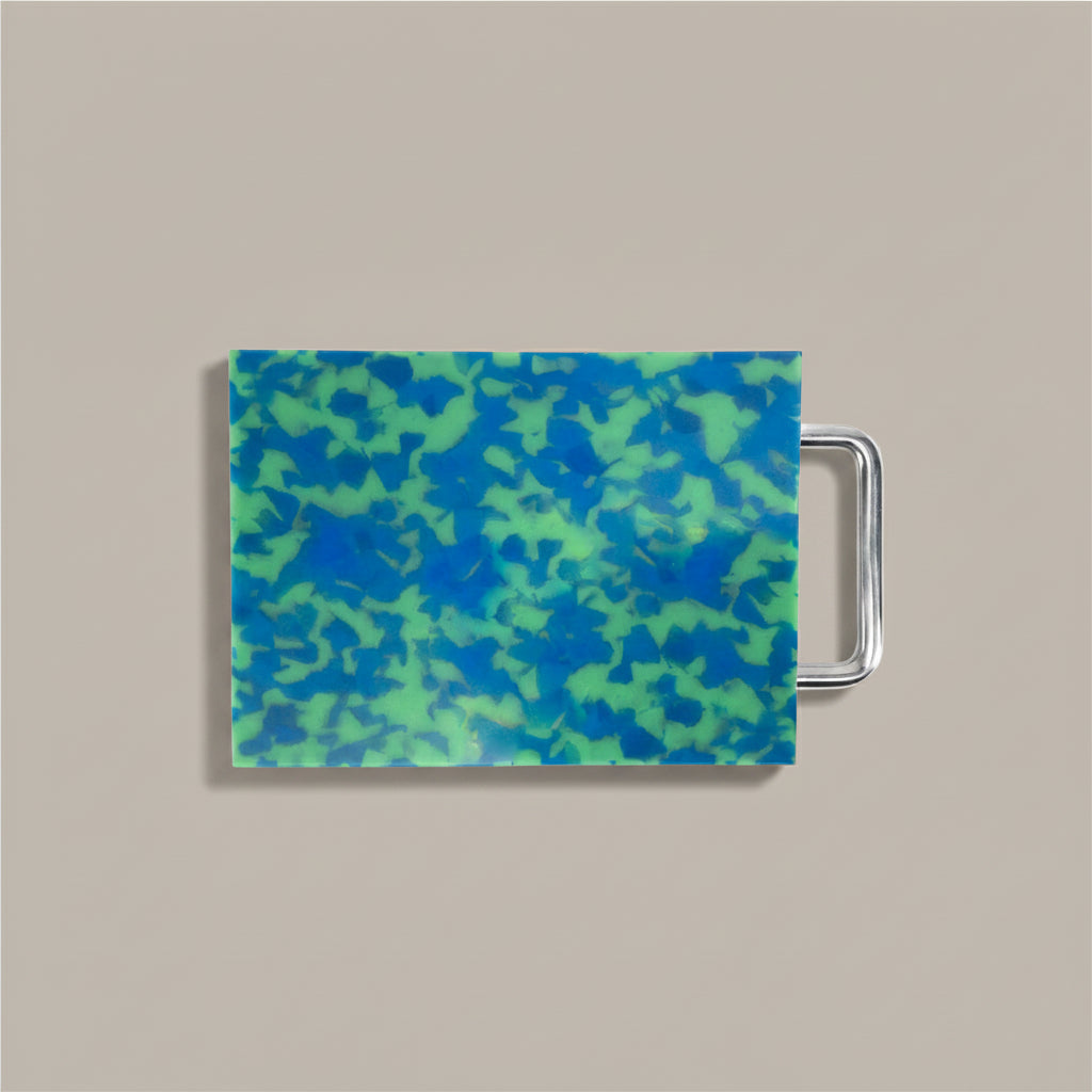Small blue and green marbled cutting board with chrome handle on white background