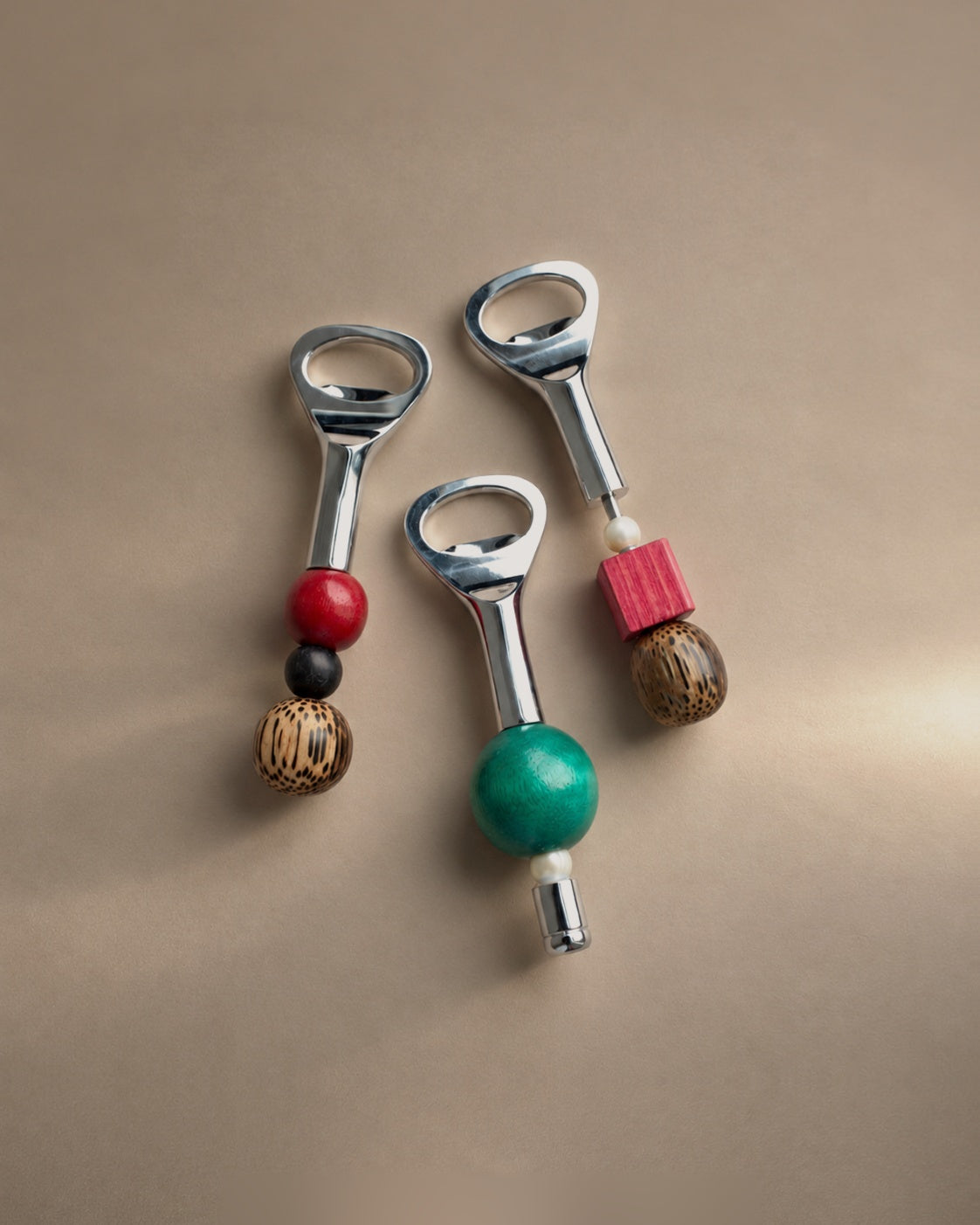 Three Yam beaded bottle openers with red, teal, pink, pearl and palm wood beads, photographed in the Son of Rand studio
