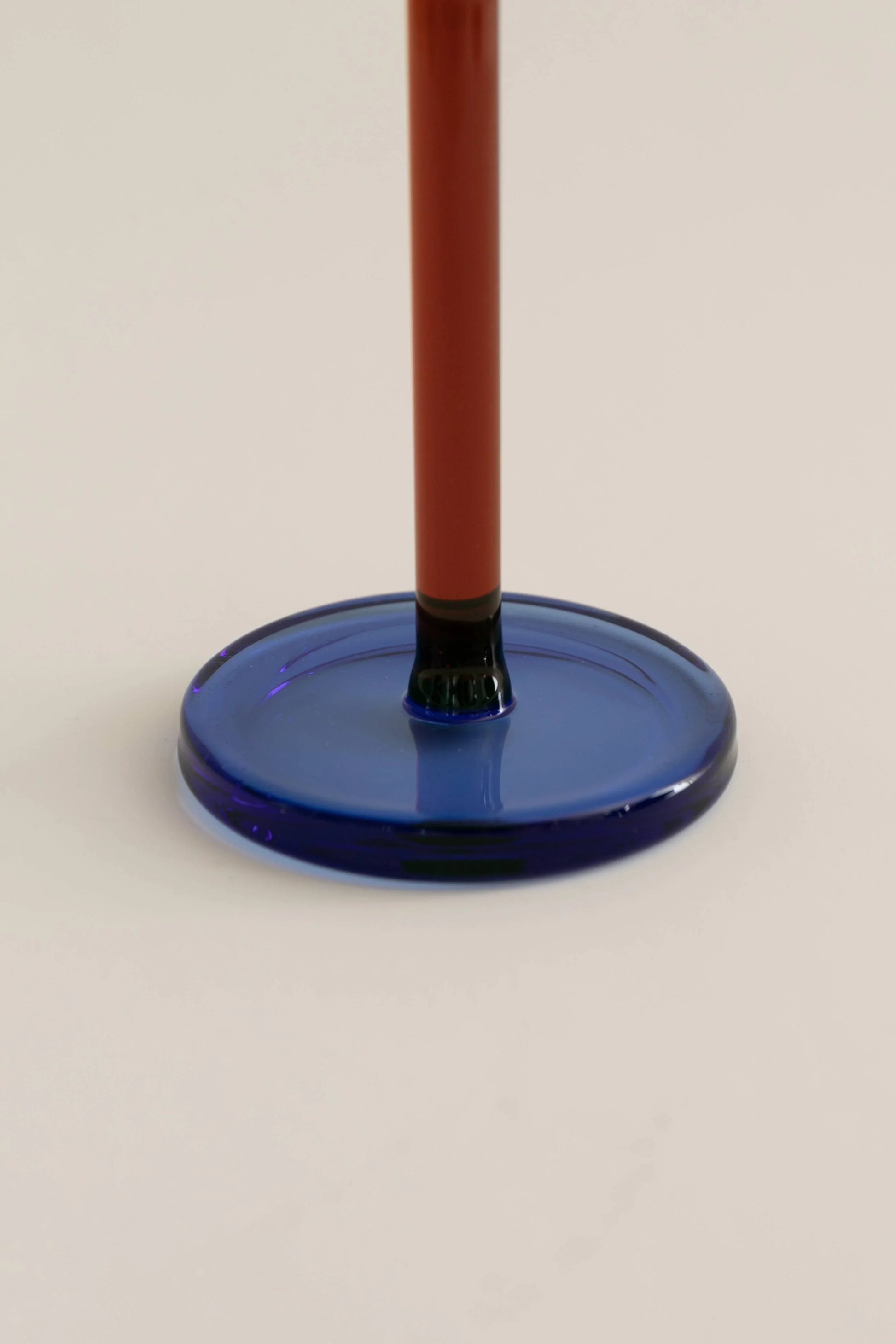 Close-up of blue glass base with red stem on light background