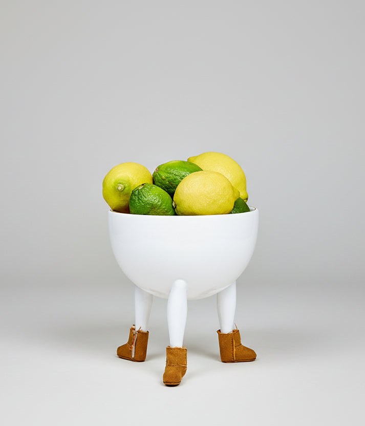 White bowl with lemons and limes on a yellow background