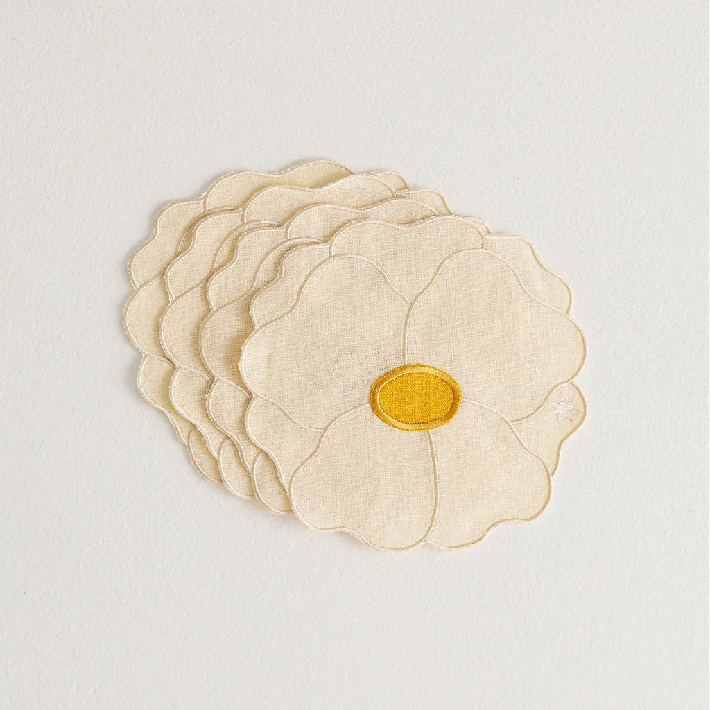 Ivory napkins shaped like wild rose flowers with yellow centers, on white background