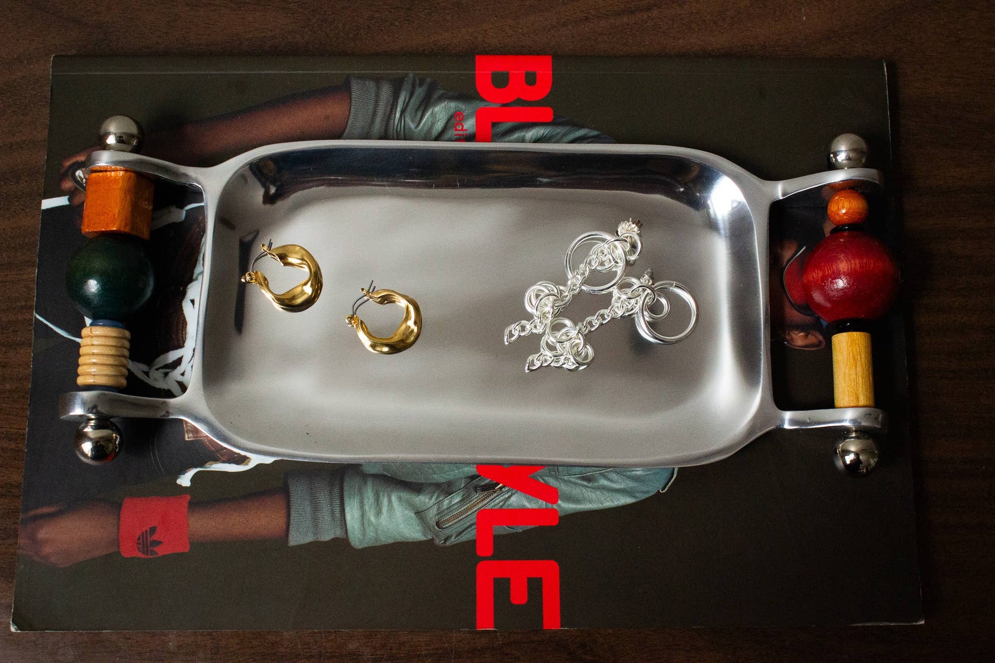 Yam Beaded Keepsake Tray styled on a stack of books holding gold and silver jewelry