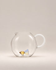 Animal Farm Fish Jug, a round clear glass jug with a milky white handle and a little glass fish inside, photographed in the Son of Rand studio