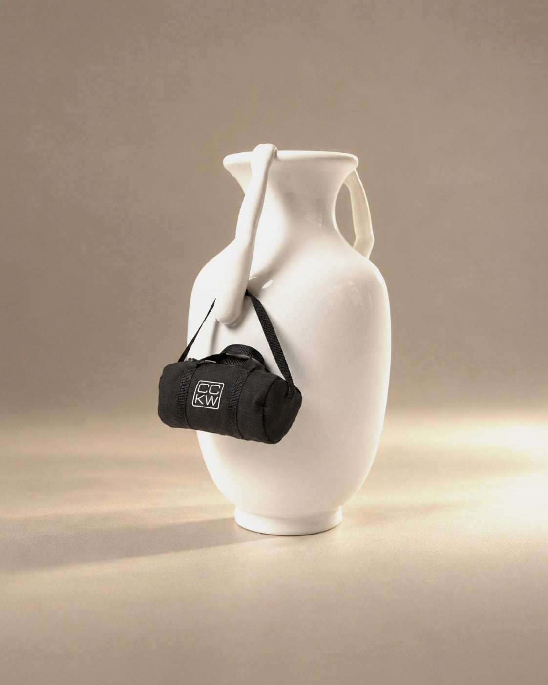 Arm Vase with Bag by Chen Chen and Kai Williams, a white ceramic amphora with arm handles and a tiny black duffel, photographed in the Son of Rand studio