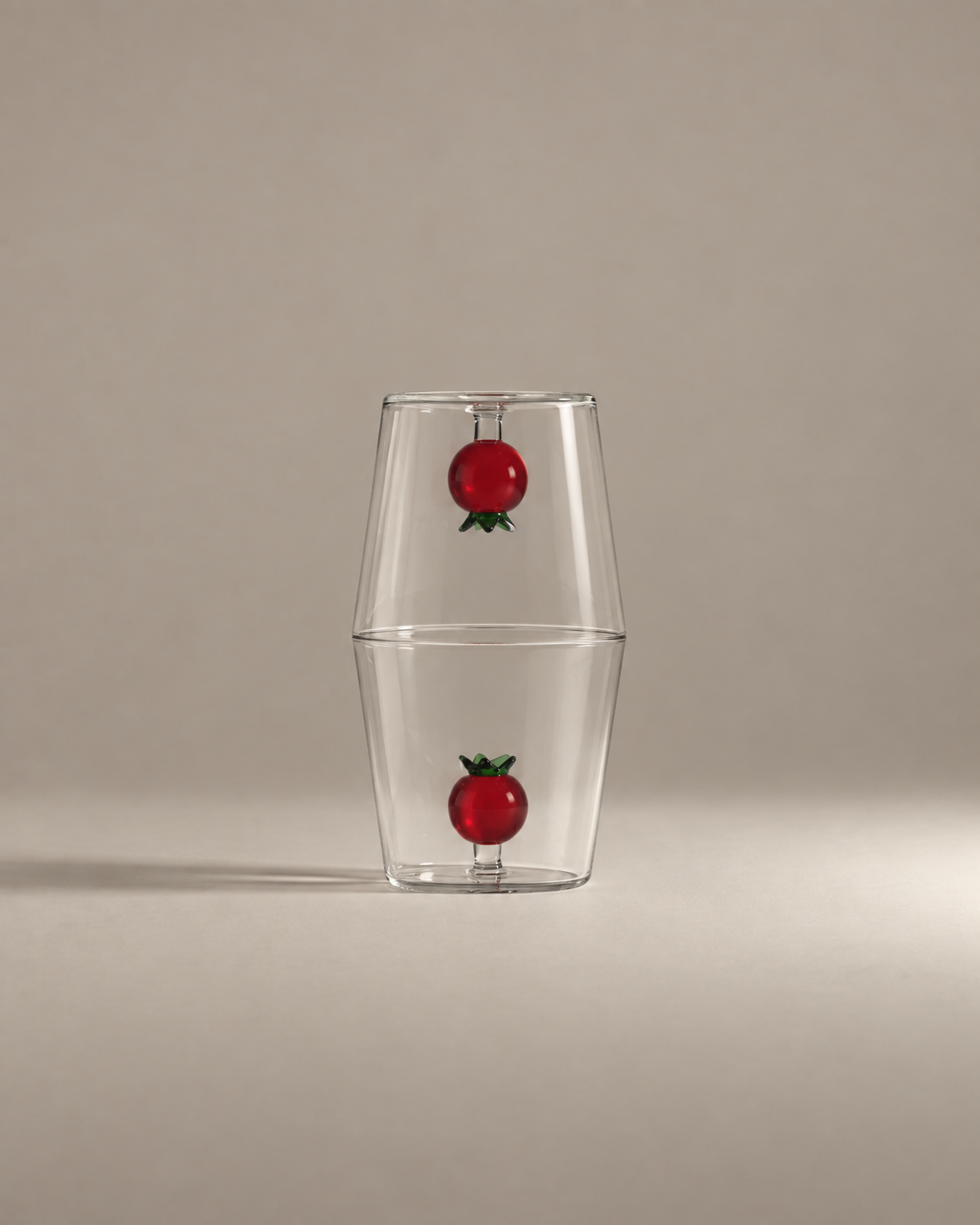 Fruit Stand Gift Set with two tomato glass tumblers stacked rim to rim on a warm greige background