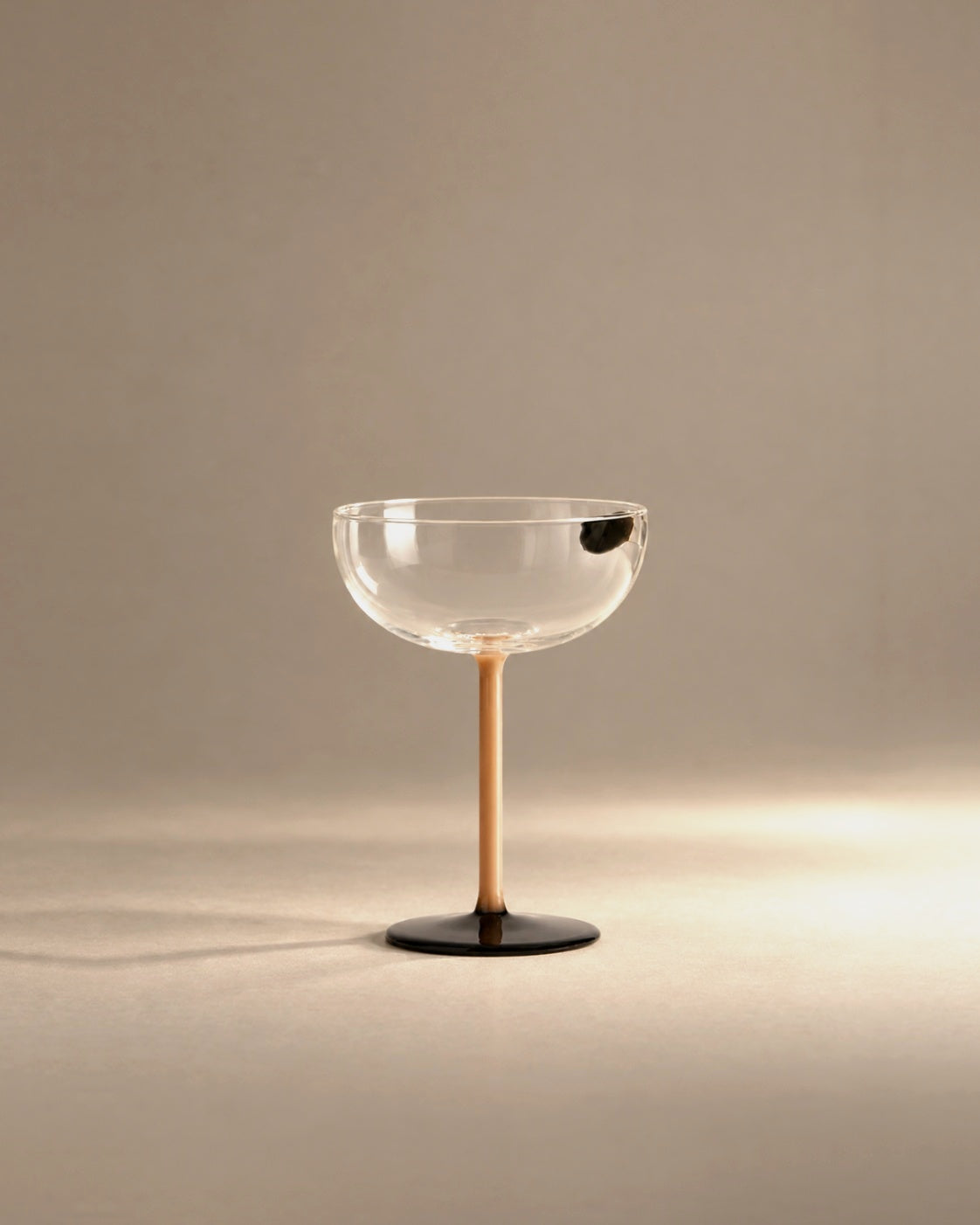 L'Espresso martini glass with amber stem and black foot, studio photo