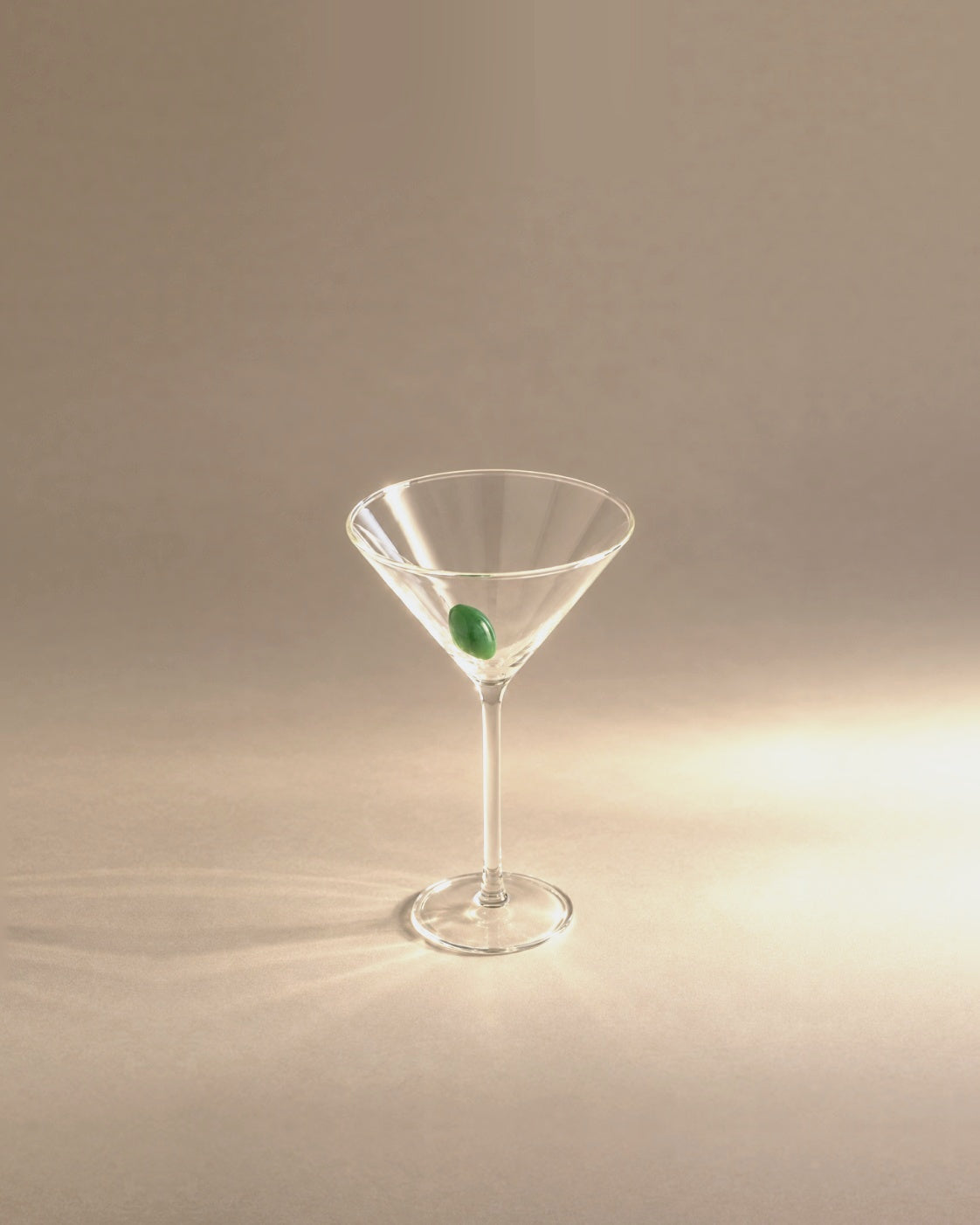 Martini Glass with green glass olive, studio photo