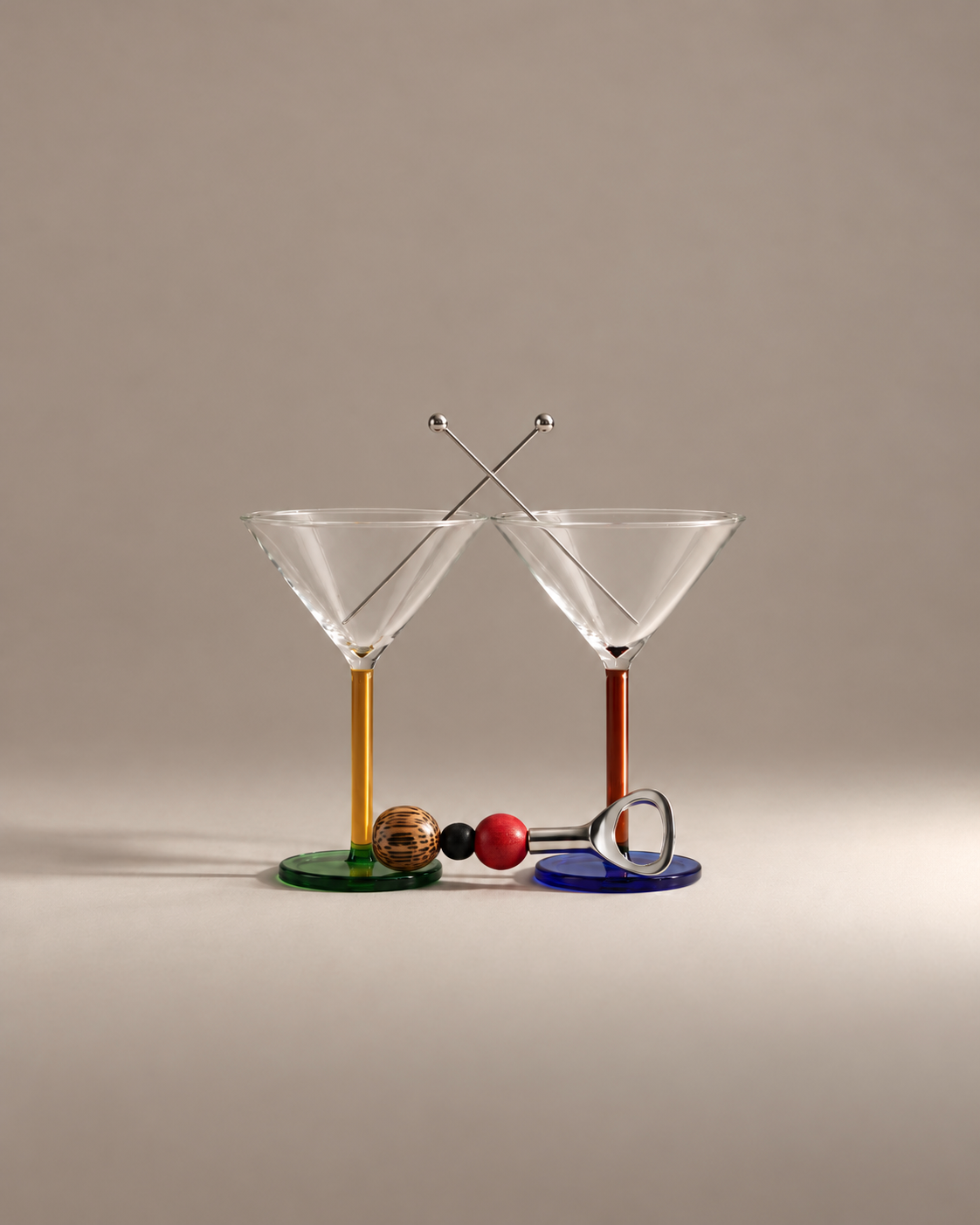 Martini Hour Gift Set: two mismatched cocktail glasses, one with a yellow stem and one amber, with crossed garnish skewers and a beaded bottle opener
