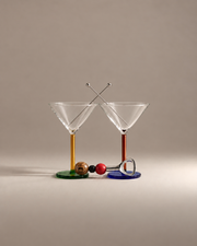 Martini Hour Gift Set: two mismatched cocktail glasses, one with a yellow stem and one amber, with crossed garnish skewers and a beaded bottle opener