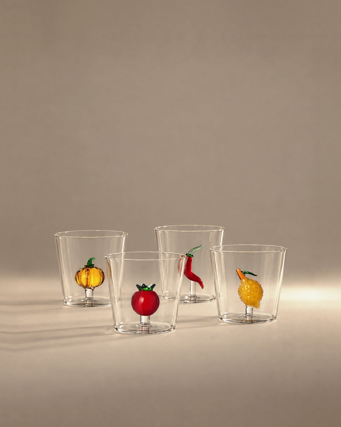 Four glass tumblers with a pumpkin, tomato, chili and lemon inside, photographed in the Son of Rand studio