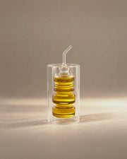 Rings Oil Bottle, a ringed glass cruet inside a clear glass cylinder, photographed in the Son of Rand studio