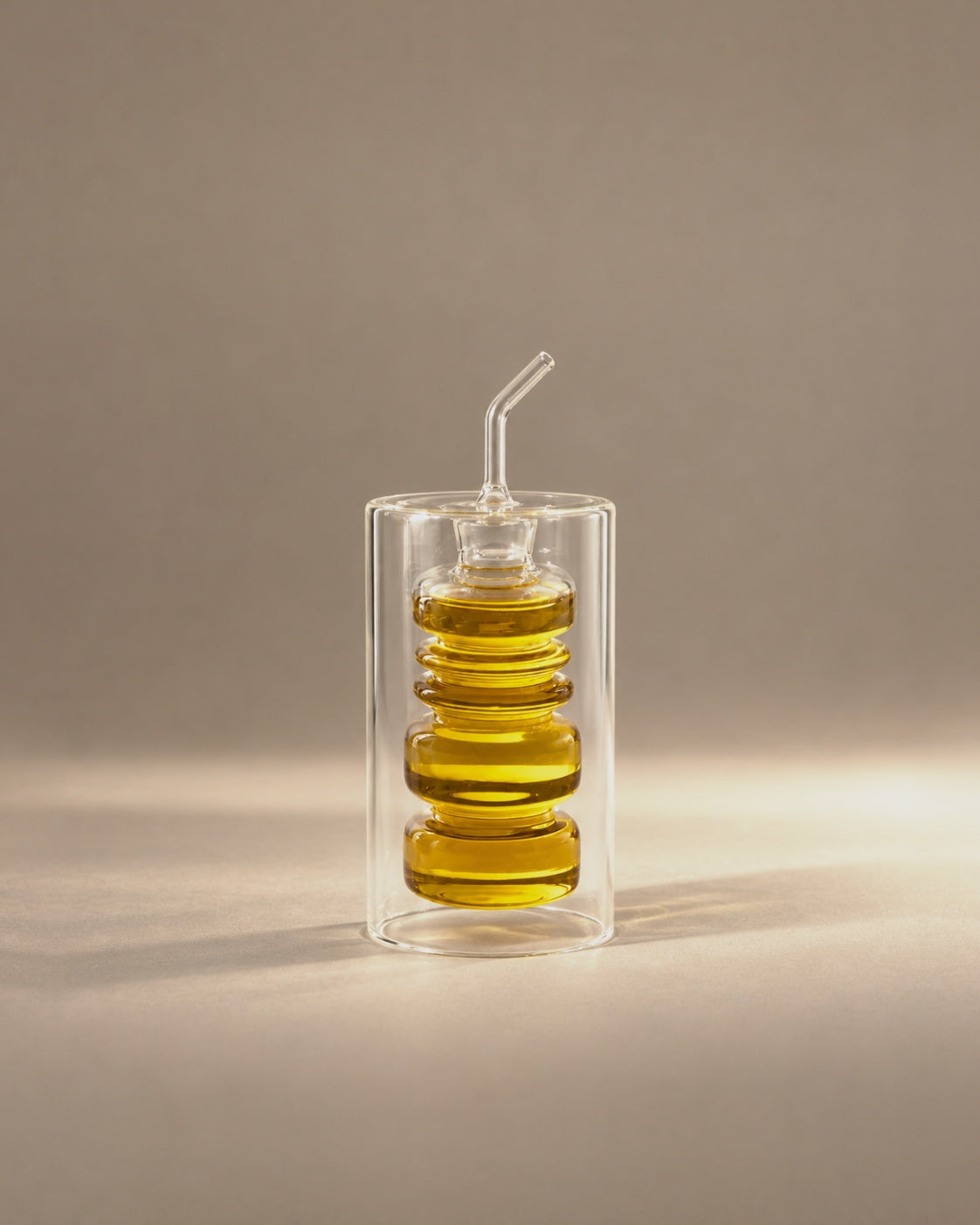 Rings Oil Bottle, a ringed glass cruet inside a clear glass cylinder, photographed in the Son of Rand studio