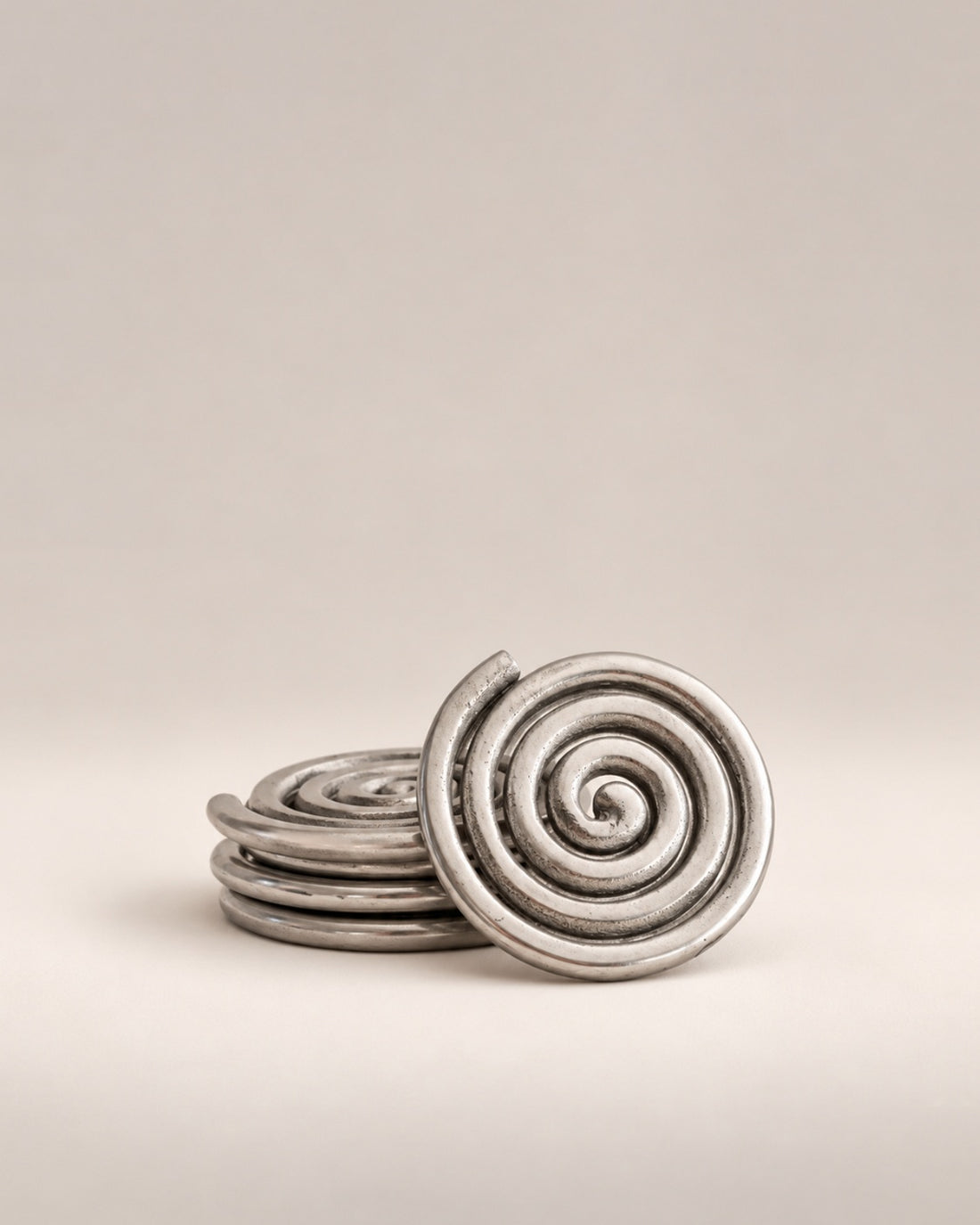 Set of four silver spiral coasters, three stacked and one standing, photographed in the Son of Rand studio