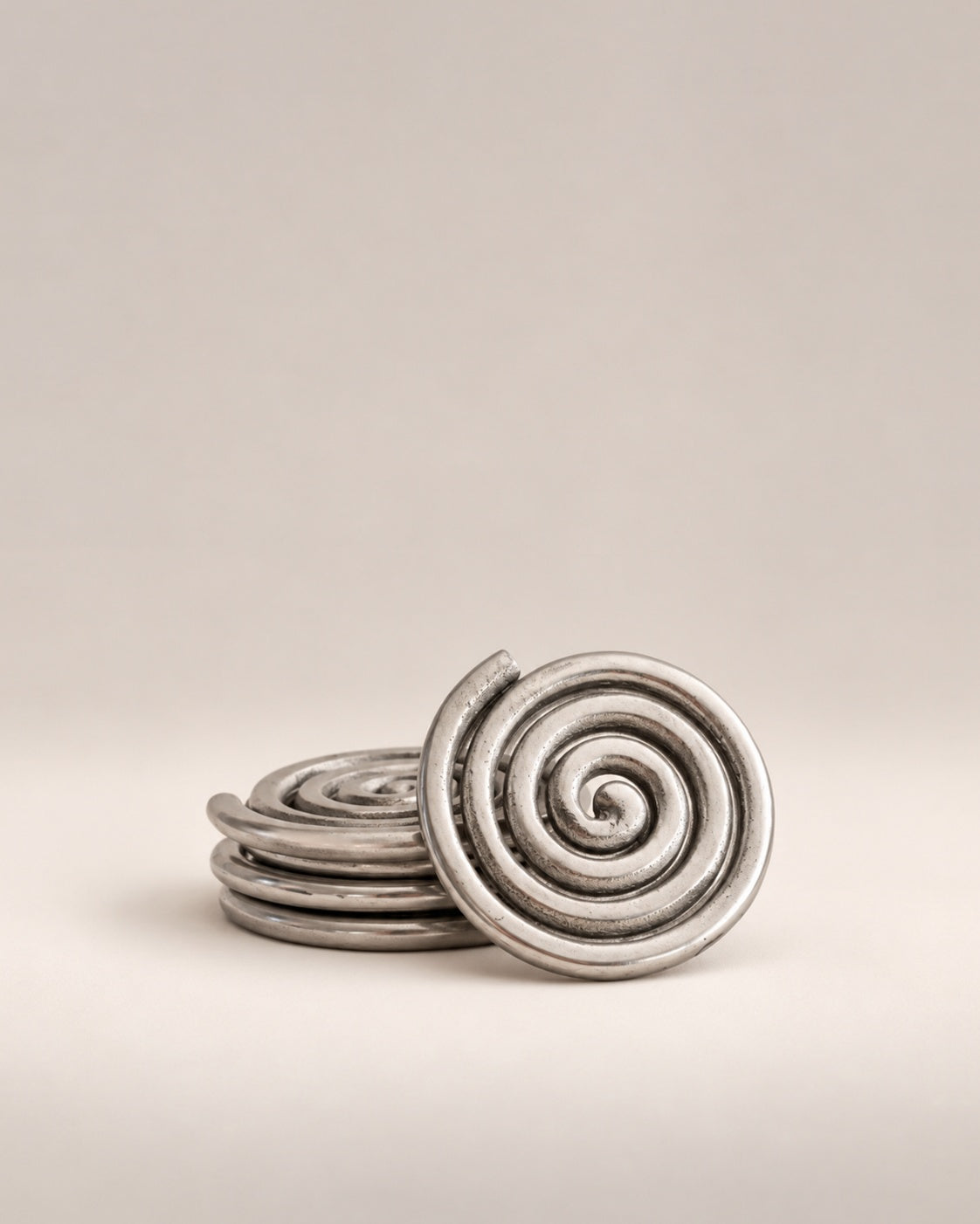 Set of four silver spiral coasters, three stacked and one standing, photographed in the Son of Rand studio