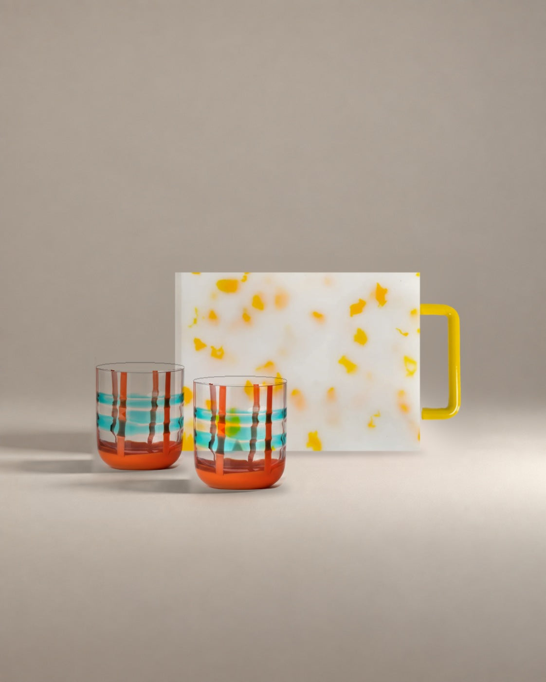 The Host Gift Set: two turquoise and red banded glass tumblers in front of a yellow confetti mini cutting board