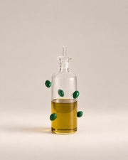 The Olive Bottle, a clear glass oil bottle with green glass olives, photographed in the Son of Rand studio