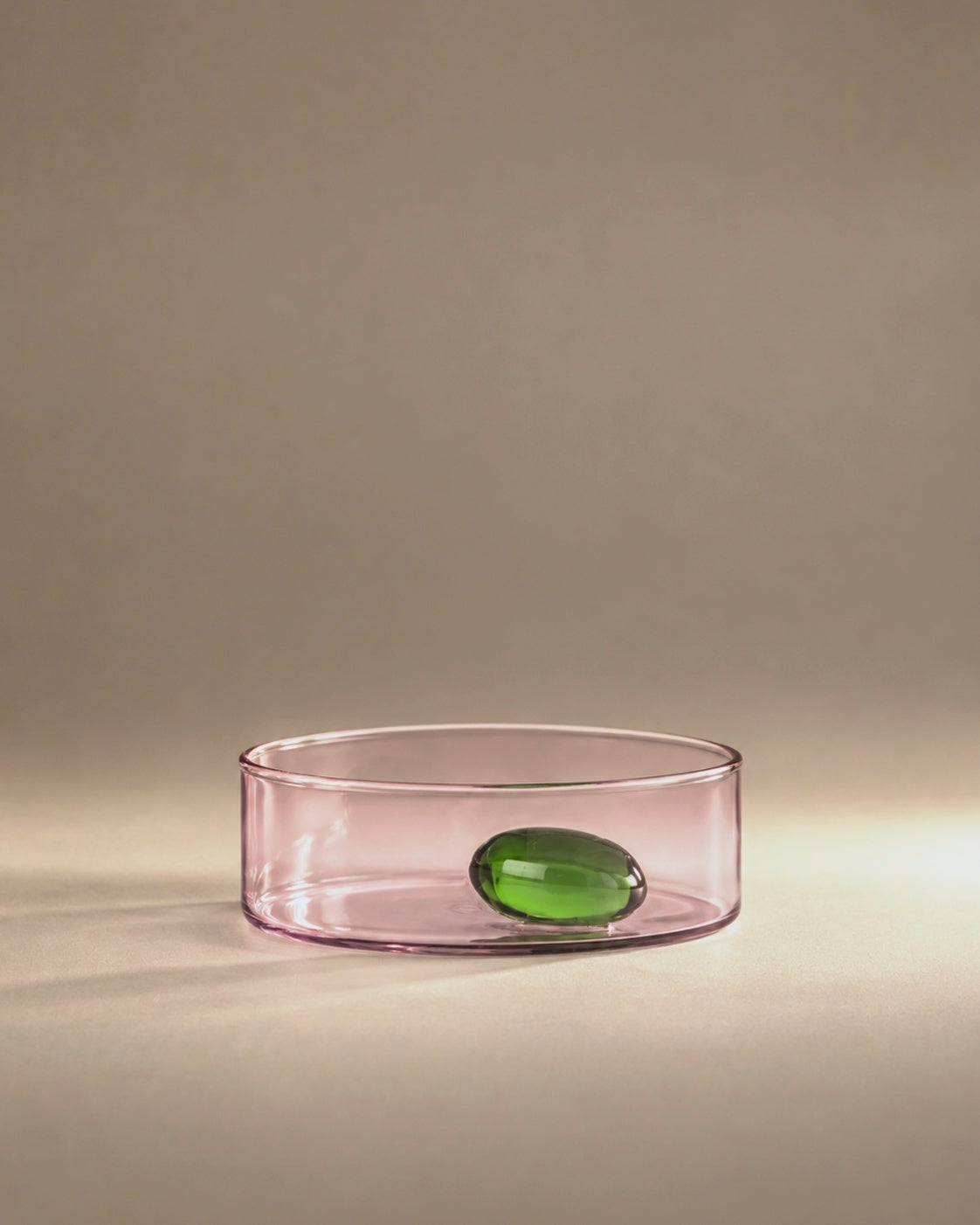 Travasi Olive Bowl in pink glass with a green glass olive, studio photograph