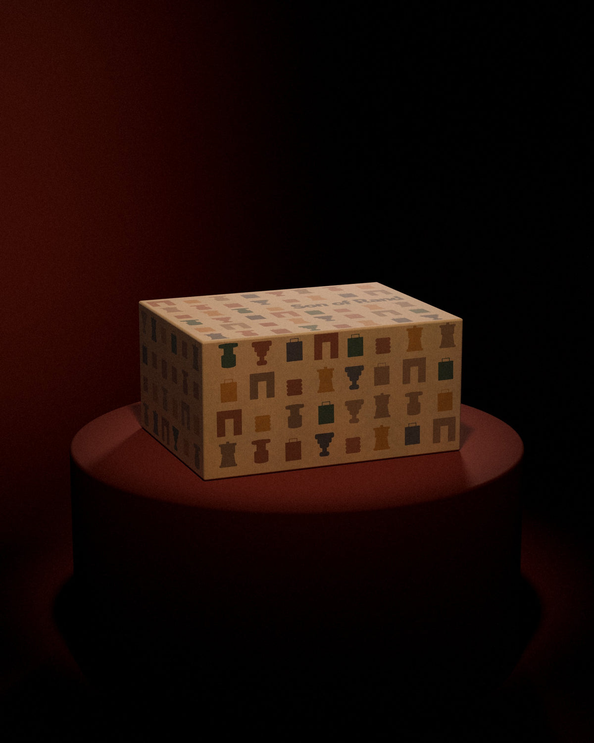 The Son of Rand Seasonal Box on an oxblood plinth under a spotlight